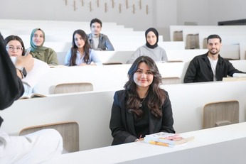 A diverse group of graduate students in an MBA vs MSA program sitting in a modern university lecture hall, attentively engaged in class.